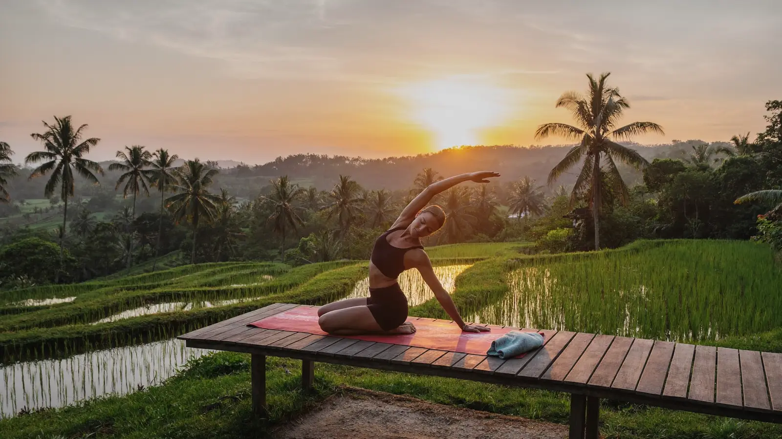 Sunset yoga session on a wooden platform over Bali rice terraces